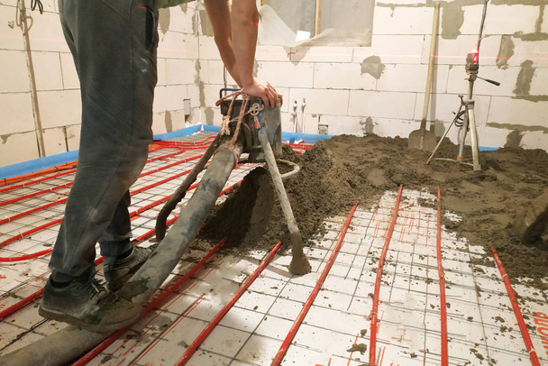 W nowo wybudowanym domu pracownik wykonuje jastrych piaskowo-cementowy do ogrzewania. - Zdjęcie, obraz