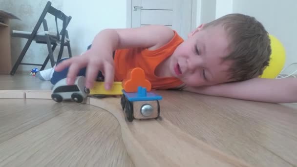 Niño de tres años juega con el tren, construye un ferrocarril de juguete en casa
. - Metraje, vídeo