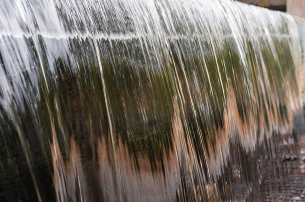 крупним планом гладка поверхня води, що тече над краєм
 - Фото, зображення