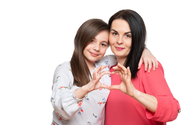 Cute girl and her mother making together heart shape hand gesture. Family love, care and support. Mom and daughter love connection concept. - Fotografie, Obrázek