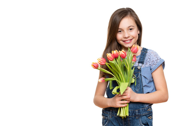Adorable little girl with beautiful smile holding bouquet of pink tulips against white background. Happy Mother's Day, Women's day, Father's day or Birthday concept. - Фото, изображение