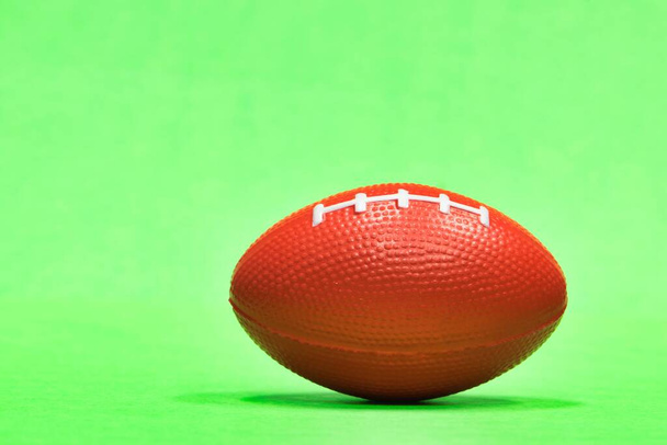 Удлиненный футбол сидя на уровне земли с зеленым фоном и копировальным пространством, Гридирон футбольный сезон в США, мяч также представляет Австралийские правила и регби
. - Фото, изображение