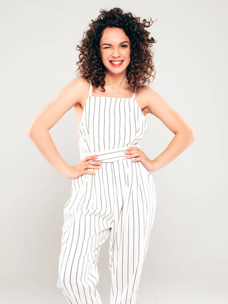 Portrait of beautiful smiling model with afro curls hairstyle dressed in summer hipster clothes.Sexy carefree girl posing in studio on gray background.Trendy funny and positive woman - Photo, Image