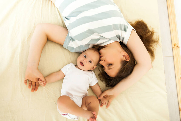šťastná matka líbání dítě ležící na posteli - Fotografie, Obrázek