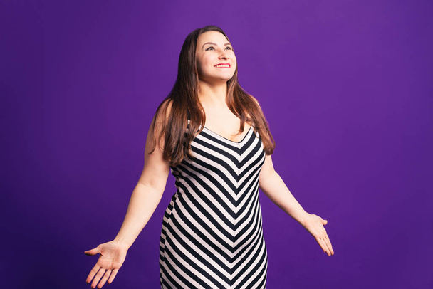 Happy pize size model in striped dress, fat woman on purple background - 写真・画像