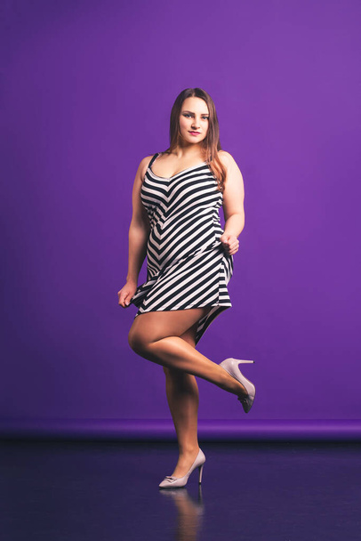 Sexy plus size fashion model in striped dress, attractive fat woman on purple background - Foto, afbeelding