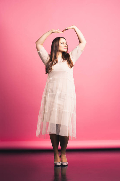 Plus size fashion model in beige dress, fat woman on pink background - Photo, Image