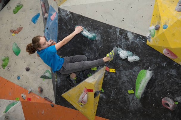 Boy on climbing wall, Bouldersport , boy climbing a rock wall indoor - Photo, Image