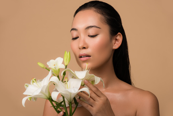 beautiful naked asian girl with white lilies isolated on beige - Fotó, kép