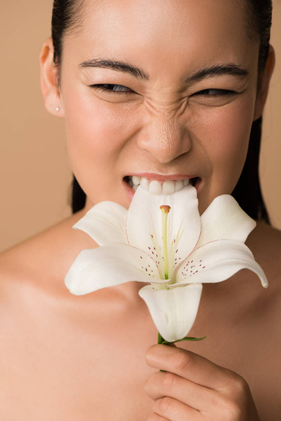 hermosa desnudo asiático chica mordiendo blanco lirio aislado en beige
 - Foto, Imagen