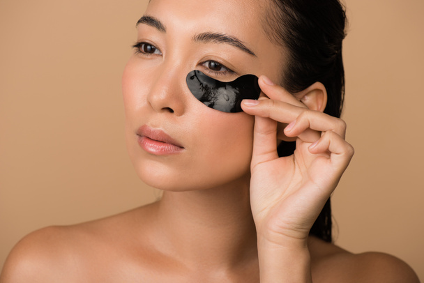 beautiful naked asian girl with black hydrogel eye patch isolated on beige - Photo, Image