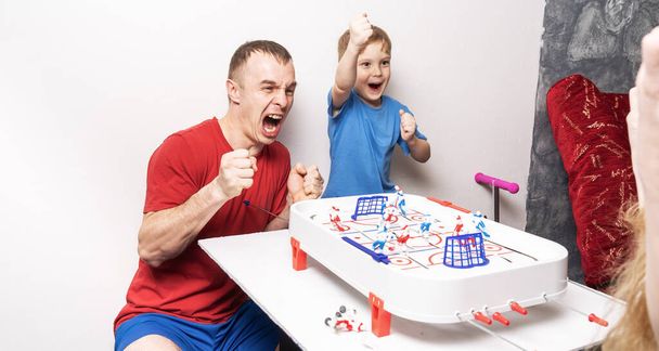 Board games: father and son play table hockey and cheer cheerfully. - Foto, Imagem