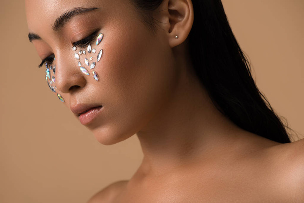 beautiful naked asian girl with rhinestones on face isolated on beige - Foto, afbeelding