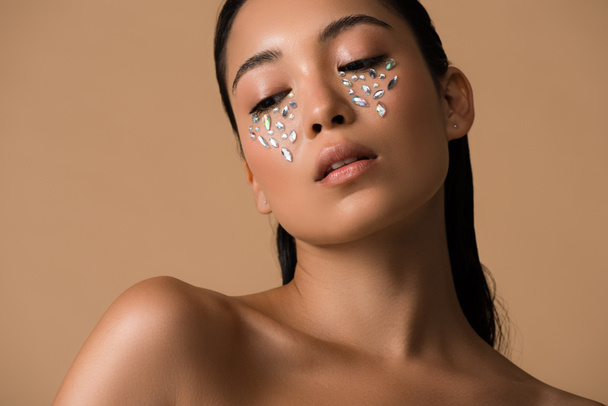 beautiful naked asian girl with rhinestones on face isolated on beige - Fotó, kép