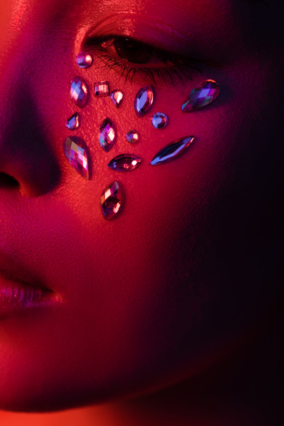 close up view of beautiful asian girl with rhinestones on face in red light - Photo, Image