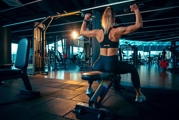 The female athlete training hard in the gym. Fitness and healthy life concept. - Foto, afbeelding