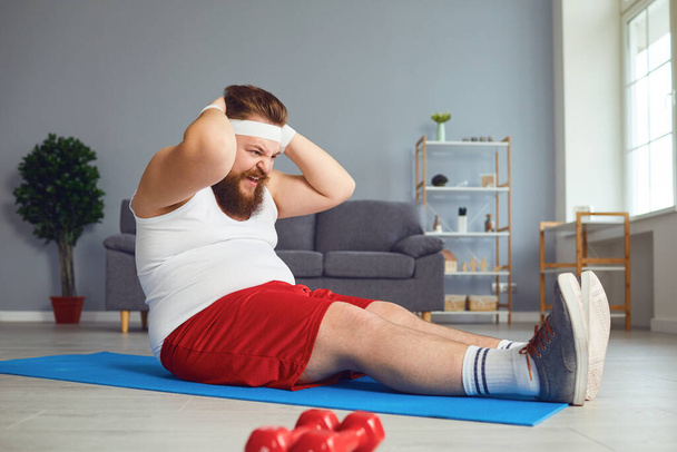 Funny fat man doing exercises in the room. - Foto, Imagen