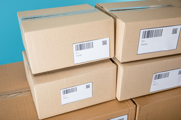 Skládané kartonové krabice s qr a čárovými kódy na kartách izolovaných na modré - Fotografie, Obrázek