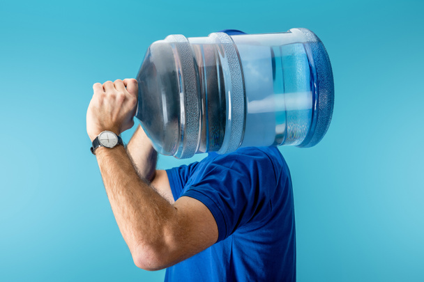 Vista lateral del mensajero sosteniendo agua embotellada aislada en azul
 - Foto, imagen