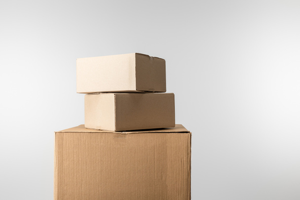 Stacked cardboard boxes isolated on grey - 写真・画像
