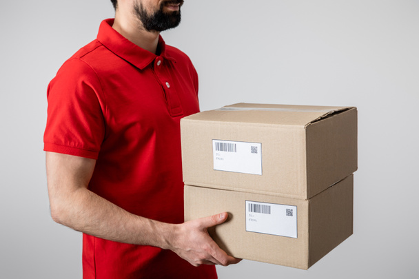 Обрізаний вид доставки людини в уніформі картонних коробок ізольовані на сірому
 - Фото, зображення