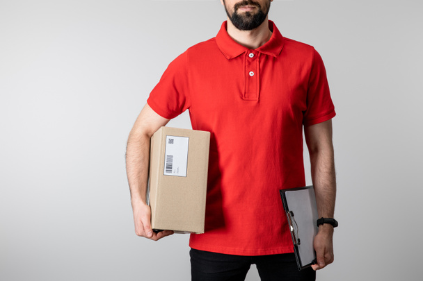 Cropped view of courier with clipboard and cardboard box isolated on grey - Photo, Image