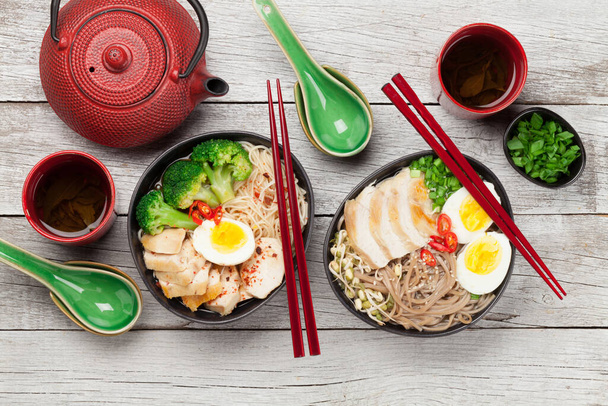木製の背景に鶏、野菜、卵とハーブティーとアジア麺ラーメンスープ。最上階平面 - 写真・画像