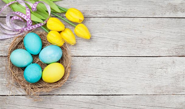 Cartão de Páscoa com ovos de Páscoa e flores de tulipa sobre fundo de madeira. Top vista plana leigos com espaço de cópia - Foto, Imagem