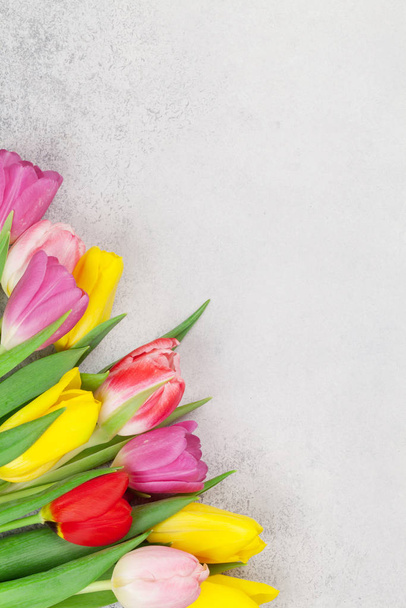 Carte de vœux de Pâques avec des fleurs de tulipes sur fond de pierre. Top vue plat étendu avec de l'espace pour vos salutations
 - Photo, image