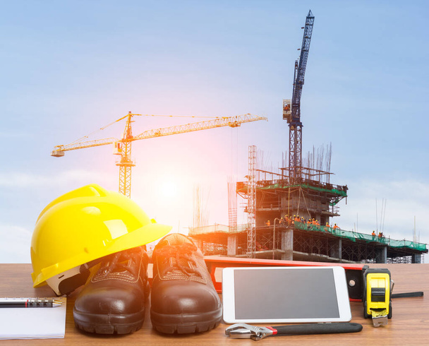 Ingeniero de mesa de trabajo con tableta y herramientas en la construcción de edificios grúa
 - Foto, Imagen