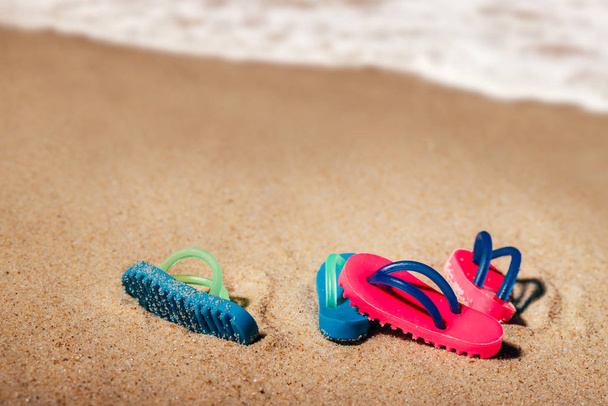 Két pár strand szandál vagy tanga a homokos tengerparton és tengerparton a háttérben ingyenes másolási hellyel - Fotó, kép
