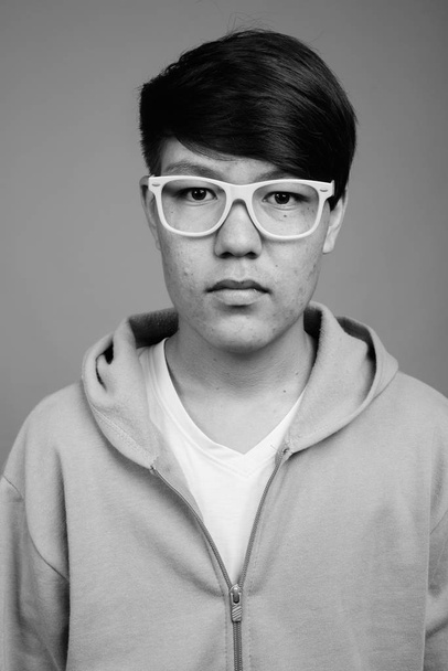 Estudio disparo de joven adolescente asiático contra fondo gris en blanco y negro - Foto, Imagen