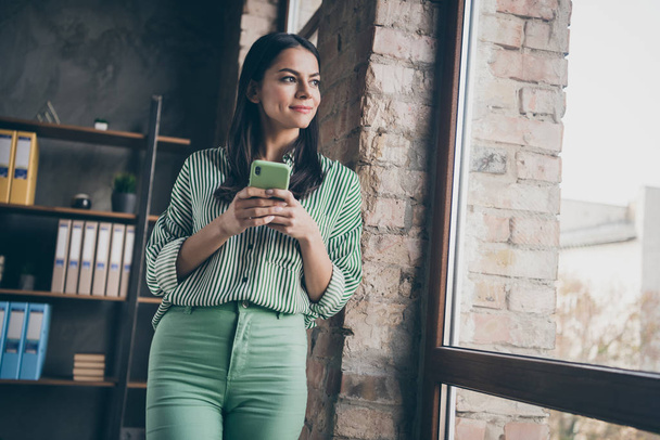 Portrait of her she nice attractive cheerful dreamy peaceful successful lady typing sms waiting boyfriend end of day at modern industrial brick loft interior style work place station - Fotó, kép