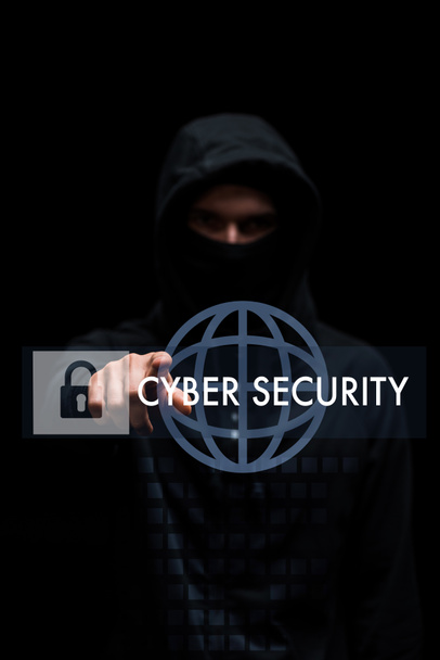Selektiver Fokus der Hacker in Kapuze zeigt mit dem Finger auf Cyber-Sicherheit Schriftzug auf schwarz  - Foto, Bild