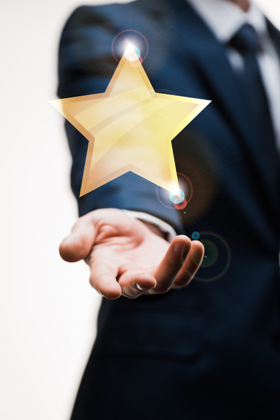 abgeschnittene Ansicht eines Geschäftsmannes im Anzug mit ausgestreckter Hand in der Nähe eines Sterns auf weißem Grund, Qualitätskonzept  - Foto, Bild