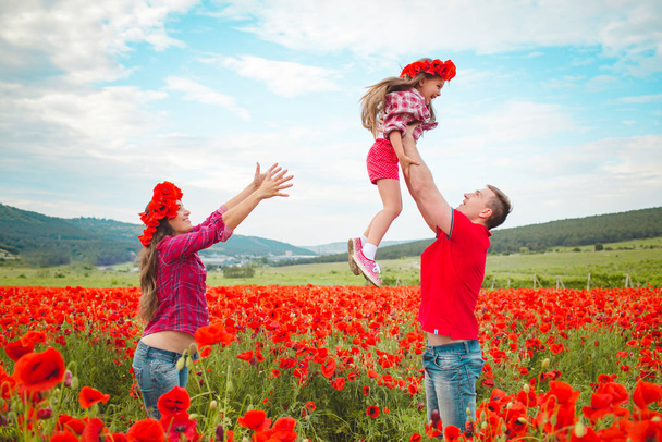 Pregnant woman her husband and their daughter in poppy field - Foto, Bild