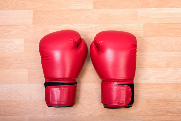 Two red boxing gloves on wooden table - Foto, afbeelding