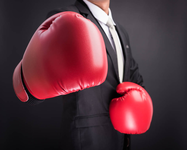 Young businessman with boxing gloves isolated on black background - Photo, image