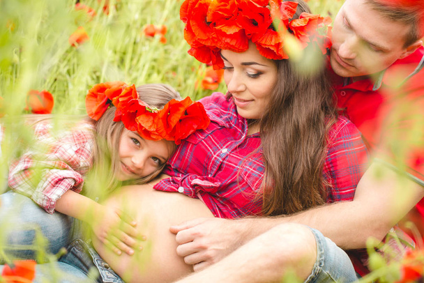 Pregnant woman her husband and their daughter in poppy field - Фото, зображення