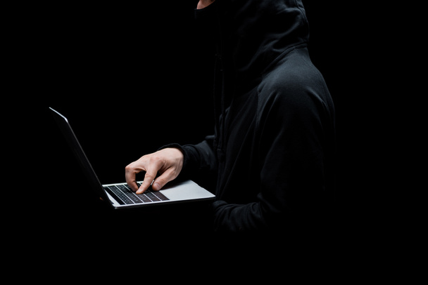 vue recadrée du pirate dans le capot à l'aide d'un ordinateur portable isolé sur noir
  - Photo, image