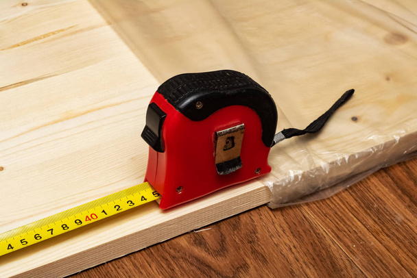 Messung eines Holzbretts mit einem Maßband - Foto, Bild