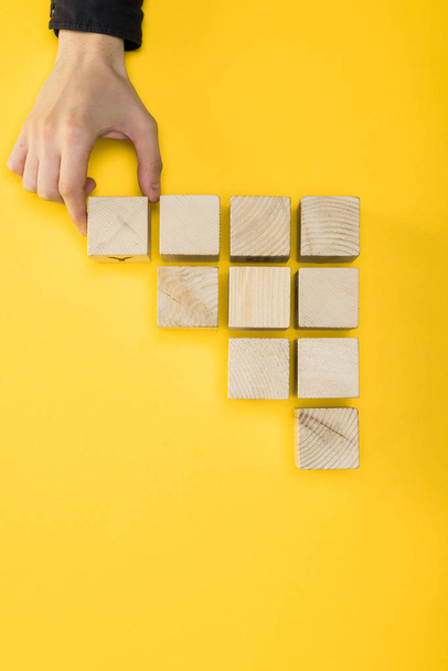 top view of man touching wooden cube isolated on yellow  - Photo, Image