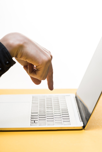 καλλιεργημένη άποψη του ανθρώπου που δείχνει με το δάχτυλο στο φορητό υπολογιστή που απομονώνεται σε λευκό  - Φωτογραφία, εικόνα