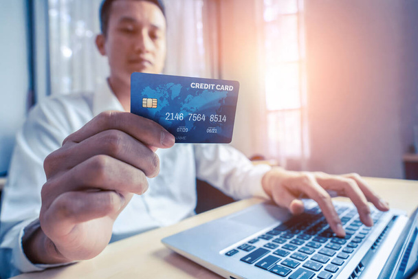 Młody człowiek korzysta z karty kredytowej na zakupy płatności online na laptopie aplikacji komputerowej lub stronie internetowej. Koncepcja handlu elektronicznego i zakupów internetowych. - Zdjęcie, obraz