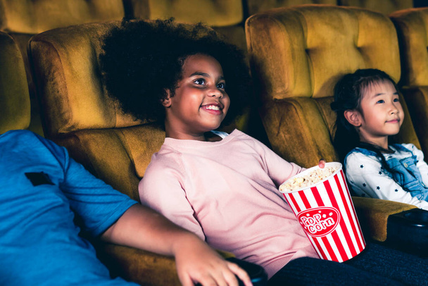 Three children having fun and enjoy watching movie in cinema - Photo, Image