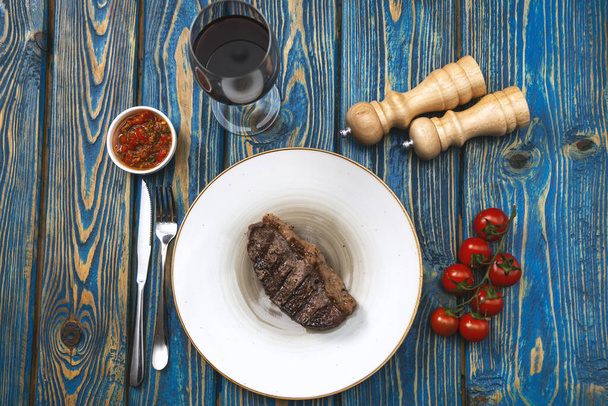 Sirloin steak  and cherry tomatoes on a plate with wine. View from above - Фото, зображення