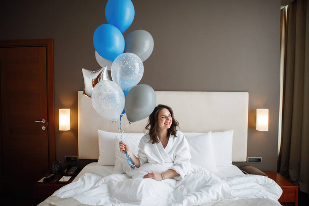 Jeune femme avec des ballons se trouve dans le lit
. - Photo, image