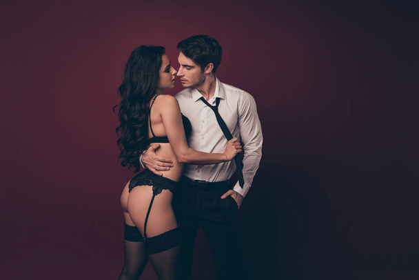 Profile photo of tender couple two people partners macho husband hold nude figure black bikini lady wife take off his suit pulling tie kiss pleasure isolated burgundy color background - Photo, Image