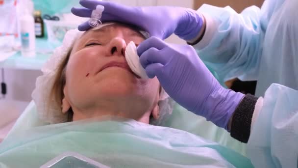 Vrouw van middelbare leeftijd 50 krijgt een tillen injectie van een injectie in het gezicht door een arts cosmetoloog. Cosmetische ingreep. close-up - Video