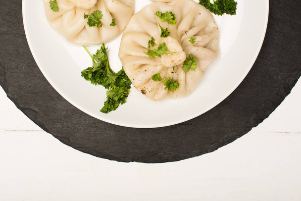 top view of delicious Khinkali with cilantro on plate on white wooden table - Фото, зображення
